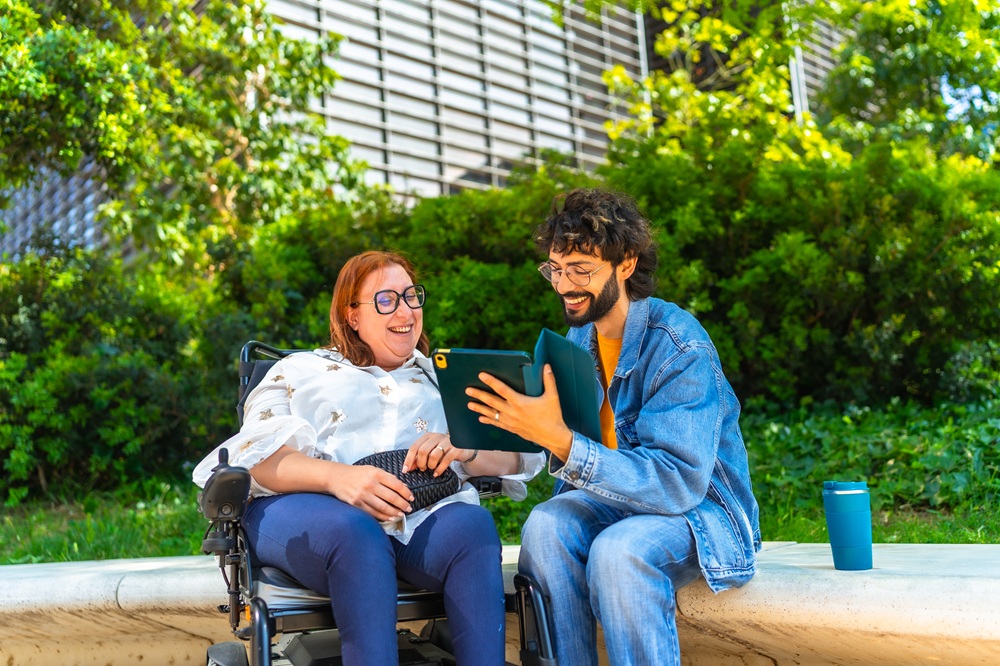 Smiling friends sharing digital tablet content outdoors in urban park