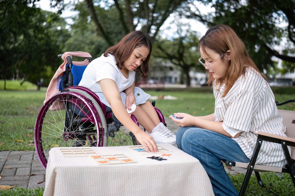 Young Disabled Woman in Wheelchair and Best Friend Enjoying a Relaxing Day in the Park Playing Games
